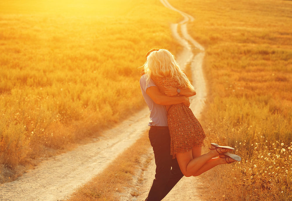 Парень держит девушку на руках на фоне красивого пейзажа