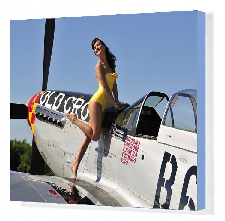 Beautiful 1940s style pin-up girl posing with a P-51 Mustang